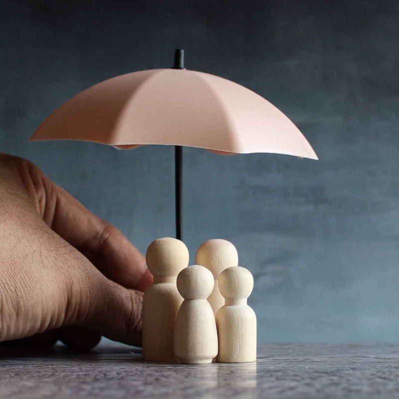Umbrella and wooden dolls with copy space. Family protection and Umbrella and wooden dolls with copy space. Family protection and insurance coverage concept.